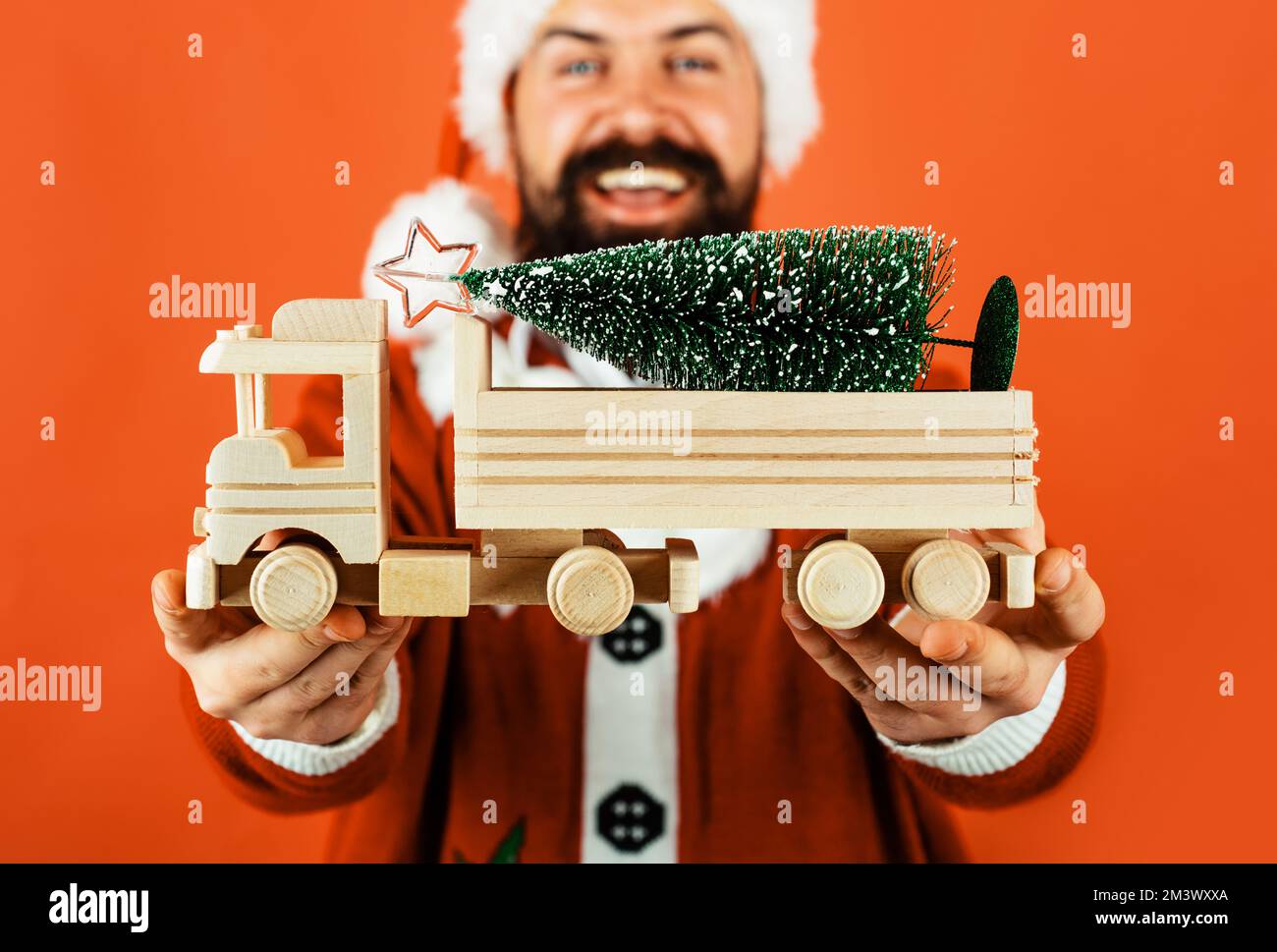 Babbo Natale uomo con piccolo albero di Natale su auto giocattolo in legno camion. Servizio di consegna. Felice Anno Nuovo. Foto Stock