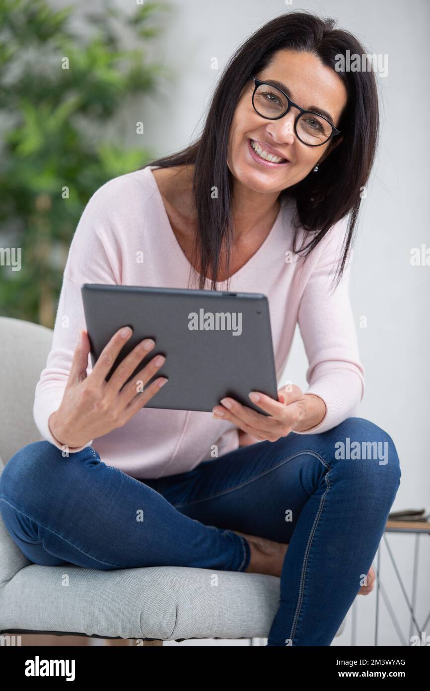 foto di una donna sorridente che naviga in rete su un tablet digitale Foto Stock