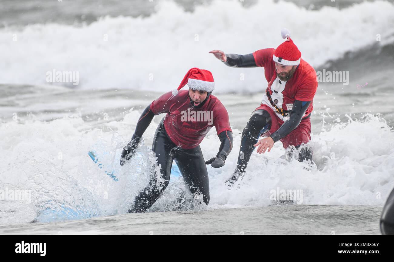 I raisers del fondo sfidano le acque ghiacciate a Langland Bay, Swansea durante l'evento annuale di Santa Surf che si svolge ogni anno presso la spiaggia di Gower per raccogliere soldi per i surfisti contro la rete fognaria e aiutare i surfisti locali a entrare nello spirito natalizio. Foto Stock