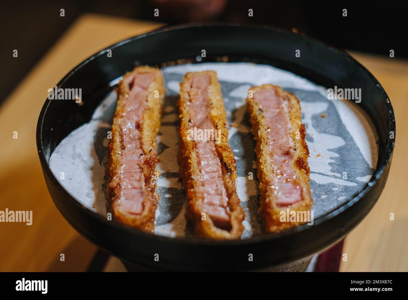 Foto ad angolo medio del katsu grigliato di manzo su un tappetino bianco per grigliate con padella nera Foto Stock