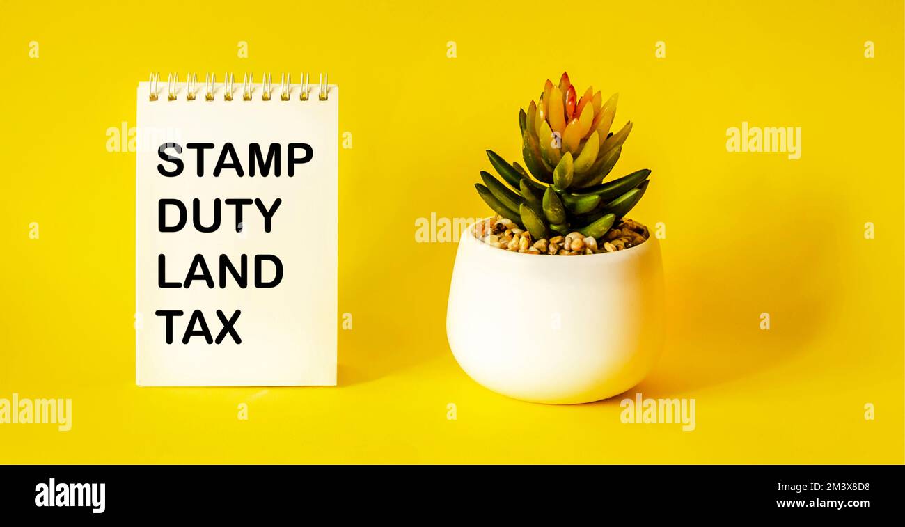 SDLT - Stamp Duty for Land Tax è scritto su un notebook su uno sfondo giallo Foto Stock