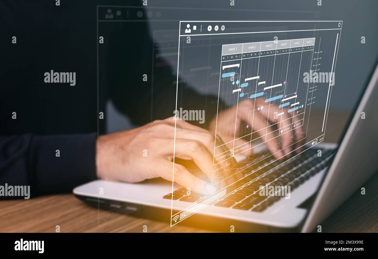 Project manager che lavora su computer portatile e aggiorna attività e fasi cardine Pianificazione dei progressi con l'interfaccia di pianificazione grafico Gantt per l'azienda su scr virtuale Foto Stock