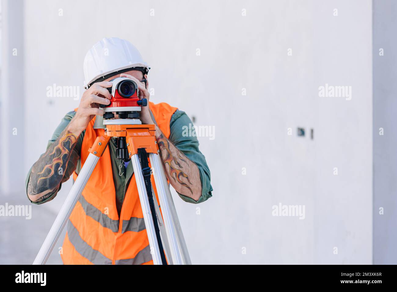 Ingegnere costruttore che lavora con la telecamera Auto Level look puntamento livellamento indagine costruzione pavimento edificio Foto Stock