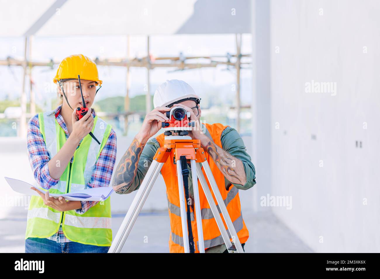 Ingegnere costruttore che lavora con la telecamera Auto Level look puntamento livellamento indagine costruzione pavimento edificio Foto Stock