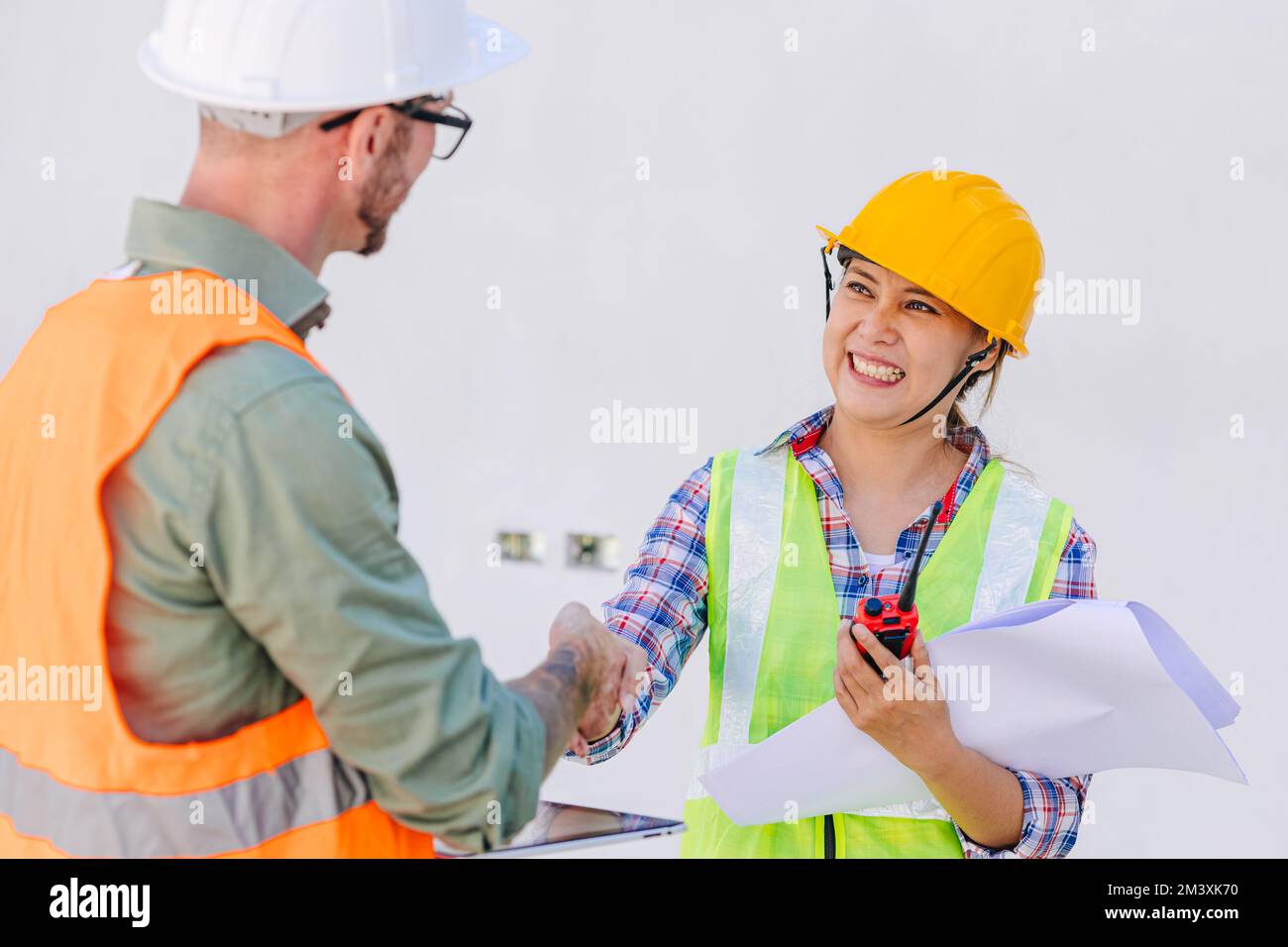 l'ingegnere costruttore di lavoratori scuotono le mani insieme sorridendo felice per la negoziazione di progetti di cooperazione Foto Stock