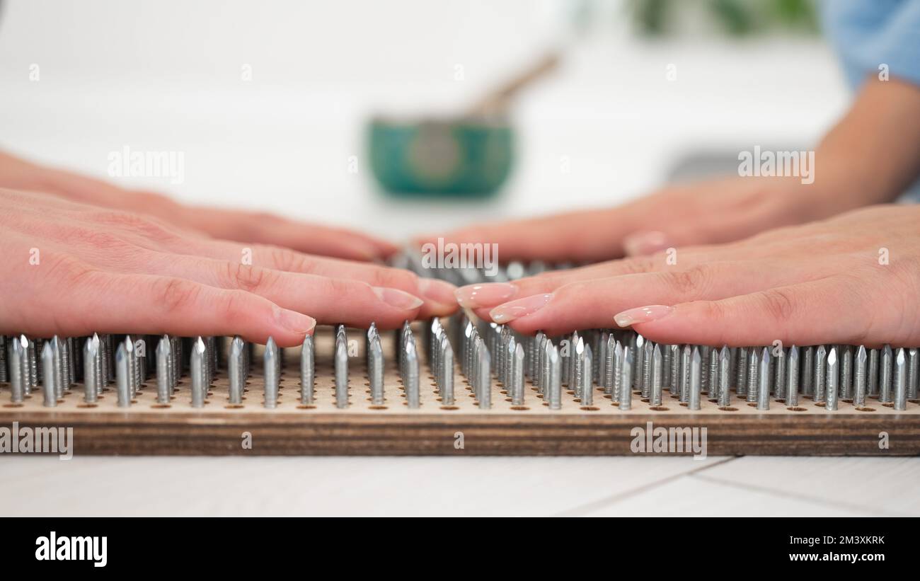 Primo piano delle mani di due donne sulle tavole di sadhu. Pratica di chiodatura. Foto Stock