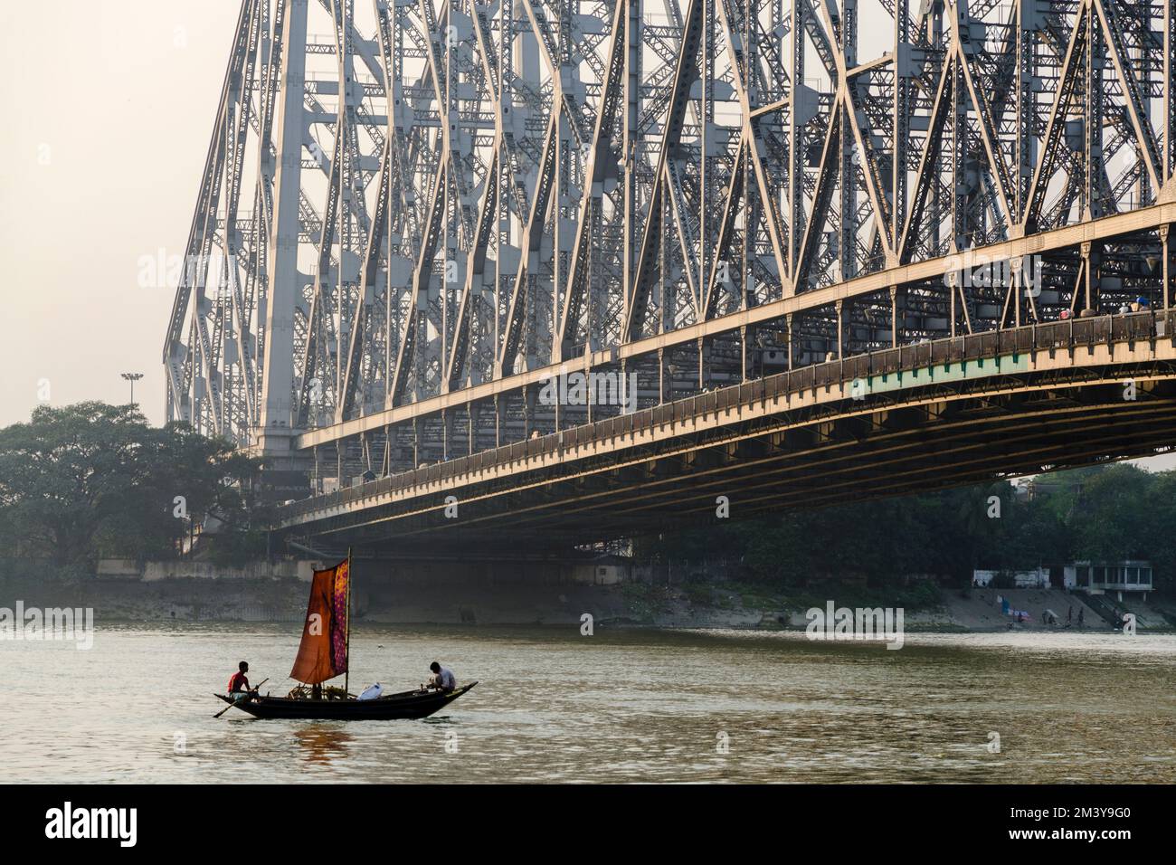 Un'antica barca a vela passa davanti all'imponente costruzione del ponte Howrah, lungo 705 metri, aperto nel 1943 Foto Stock