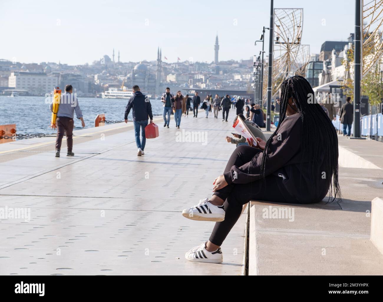 Donna che legge un libro sul mare. Istanbul - Turchia 19.12.2022 Foto Stock