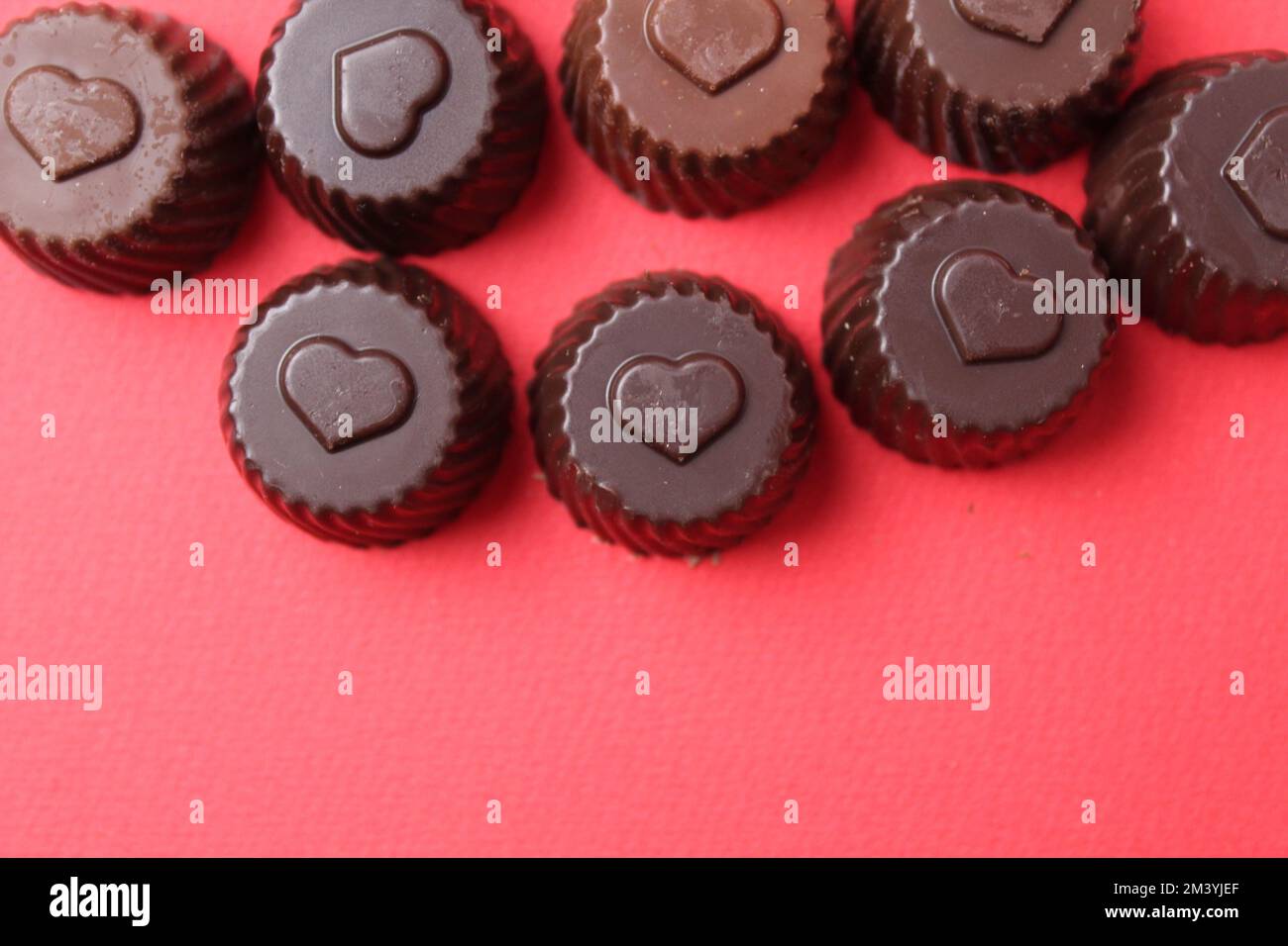 caramelle al cioccolato con il simbolo del cuore. San Valentino dei dolci al cioccolato. Bonbon caramella su sfondo rosso con spazio per il copyspace Foto Stock