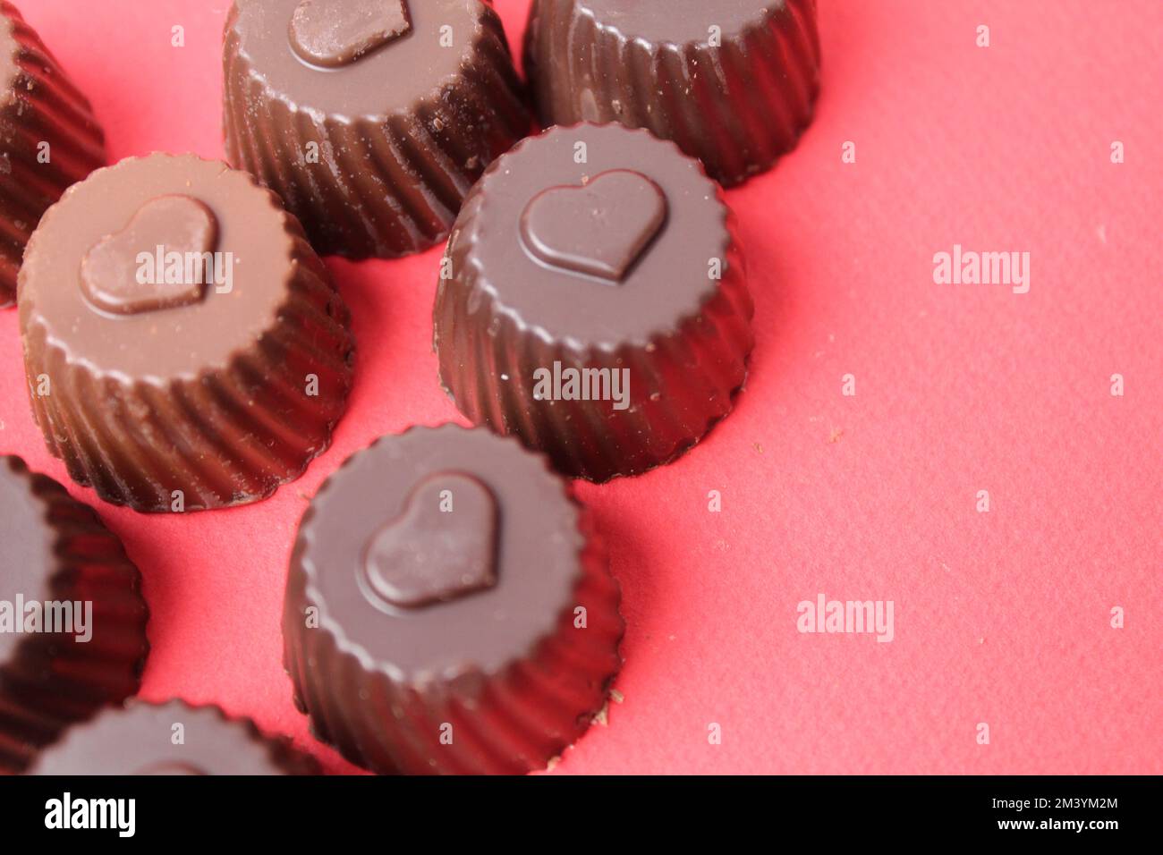 caramelle al cioccolato con il simbolo del cuore. San Valentino dei dolci al cioccolato. Bonbon caramella su sfondo rosso con spazio per il copyspace Foto Stock