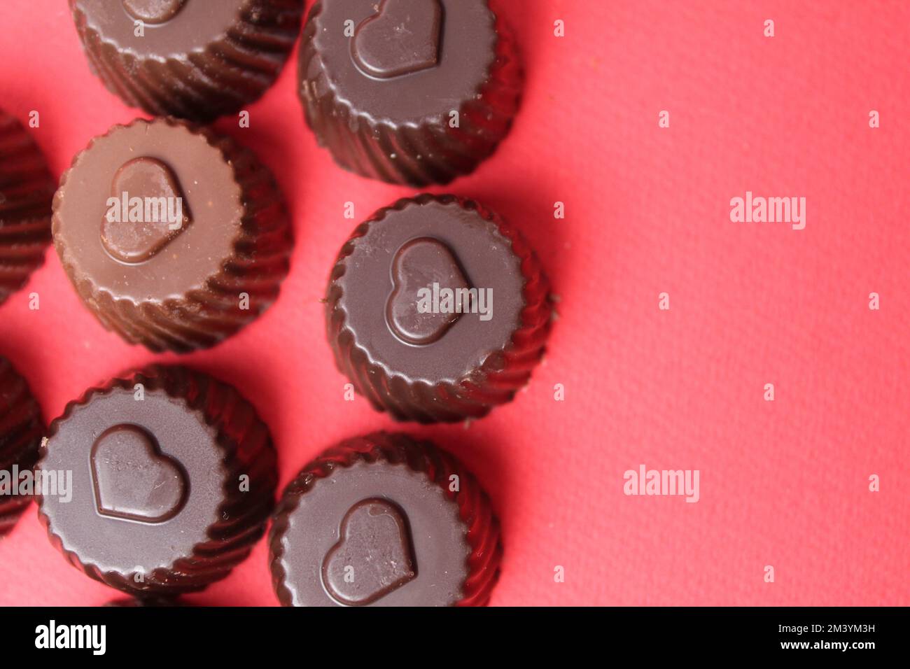 caramelle al cioccolato con il simbolo del cuore. San Valentino dei dolci al cioccolato. Bonbon caramella su sfondo rosso con spazio per il copyspace Foto Stock