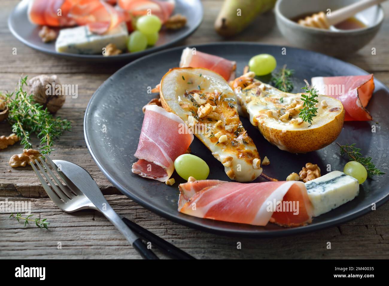 Pere al forno farcite con formaggio gorgonzola, servite con noci e pancetta altoatesina Foto Stock