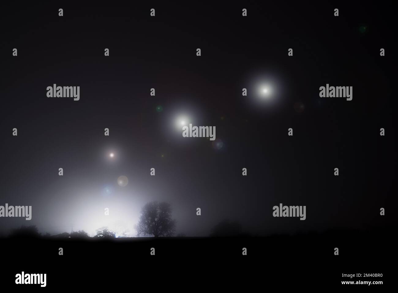 Luci UFO aliena scintillanti che galleggiano nel cielo. In una notte d'inverni con nebbia spoky Foto Stock
