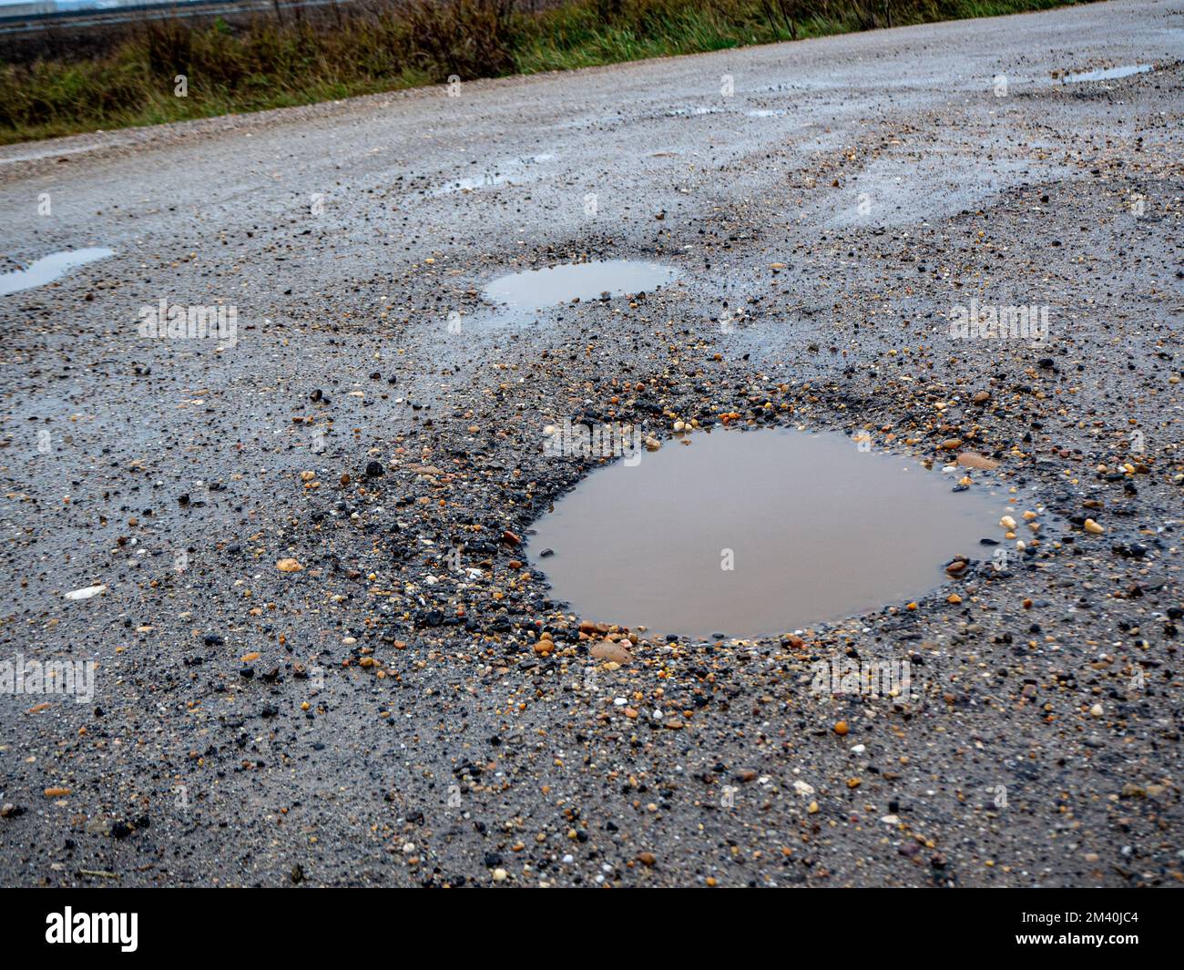 In prossimità di grandi buche con sporco acqua di pioggia della strada. Foto Stock