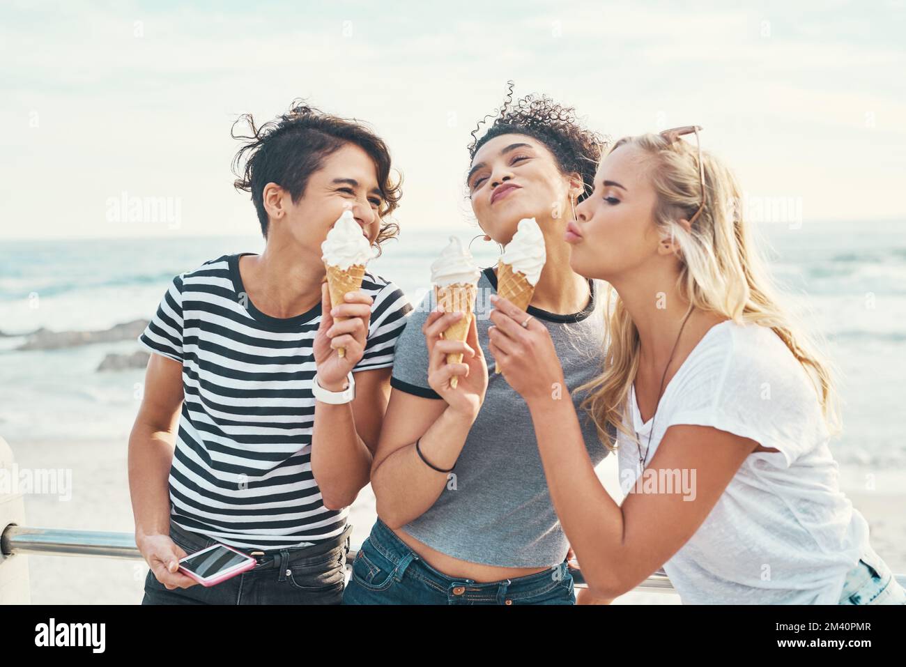 Il gelato dona a tutti un umore migliore. tre amici mangiano ghiaccio mentre fuori sul lungomare. Foto Stock