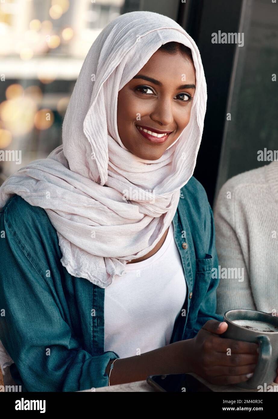 Questo è uno dei miei luoghi preferiti. Ritratto corto di una giovane donna attraente che ha caffè con la sua amica femmina in un bar mentre vestito in hijab Foto Stock