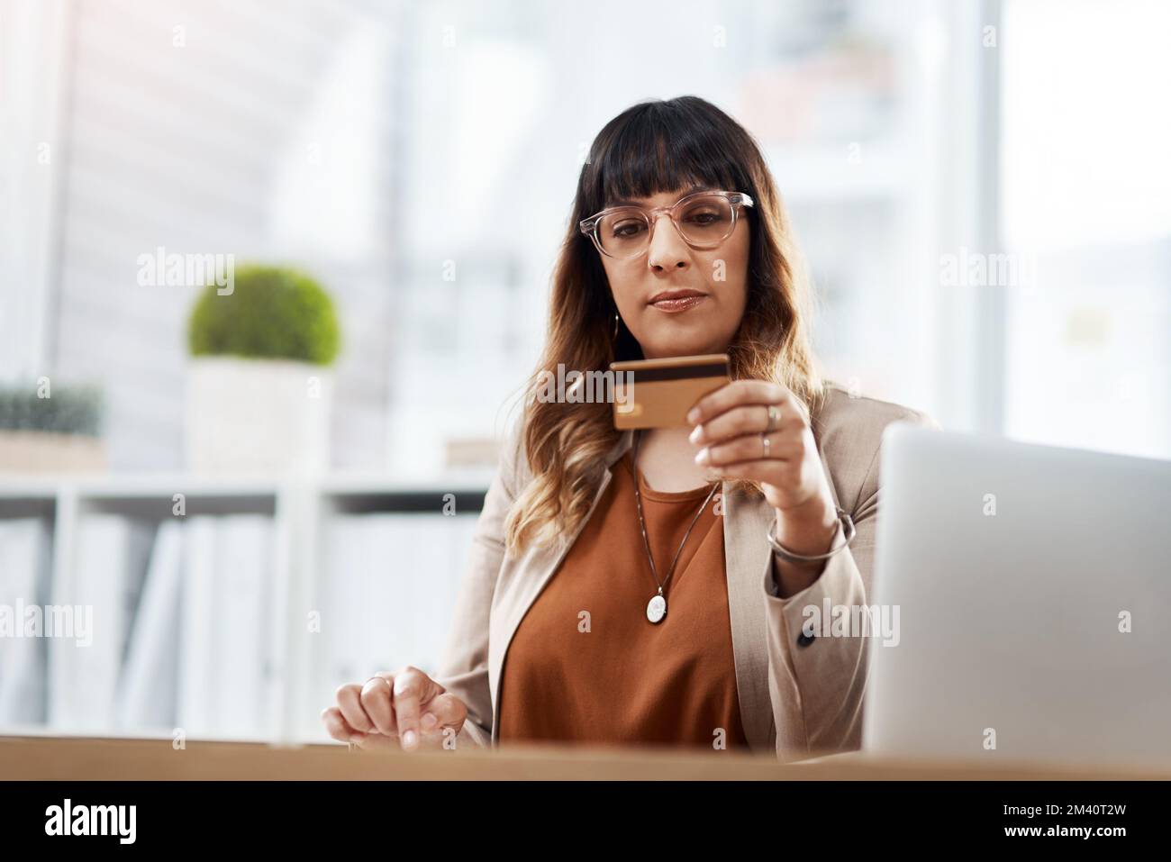 Penso che meriti di viziarmi un po'. una bella giovane donna d'affari che usa un tablet digitale e una carta di credito per fare acquisti online nel suo ufficio. Foto Stock