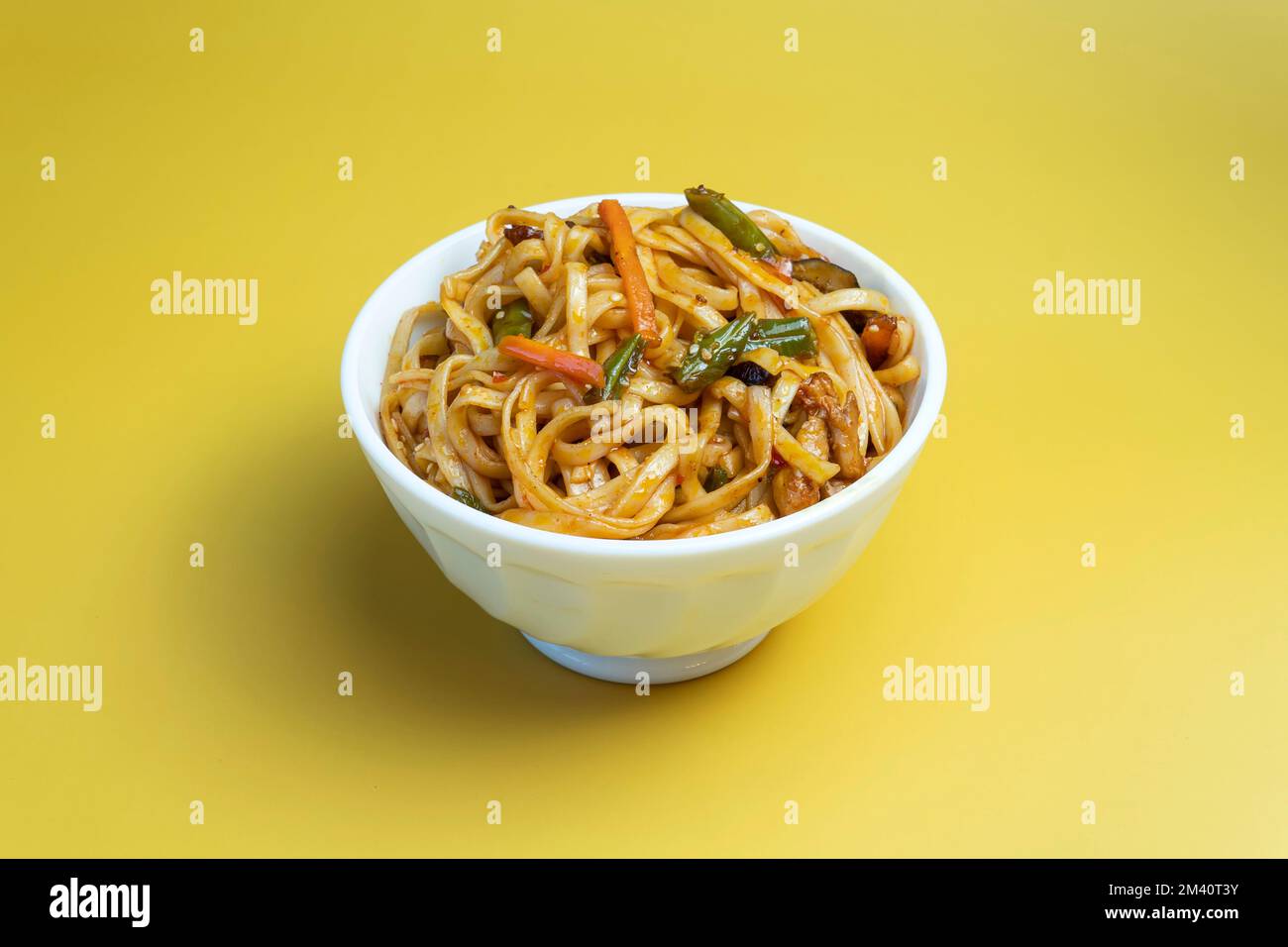 Tagliatelle con carote e verdure di pollo e fagioli di carne su sfondo giallo, vista dall'alto colore giallo brillante sfondo. Foto Stock