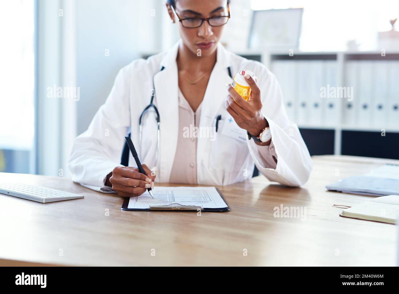Dispensazione di farmaci direttamente dalla stanza dei medici. un giovane medico che compila un modulo per una prescrizione medica nella sua sala di consulenza. Foto Stock