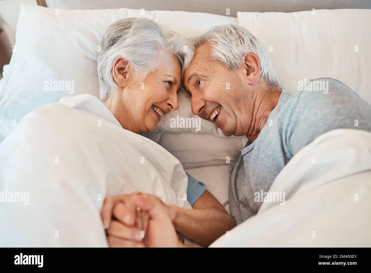 Finché ho te, ho tutto. una coppia anziana affettuosa che si guarda amorevolmente mentre si posa a letto nella loro casa di cura. Foto Stock