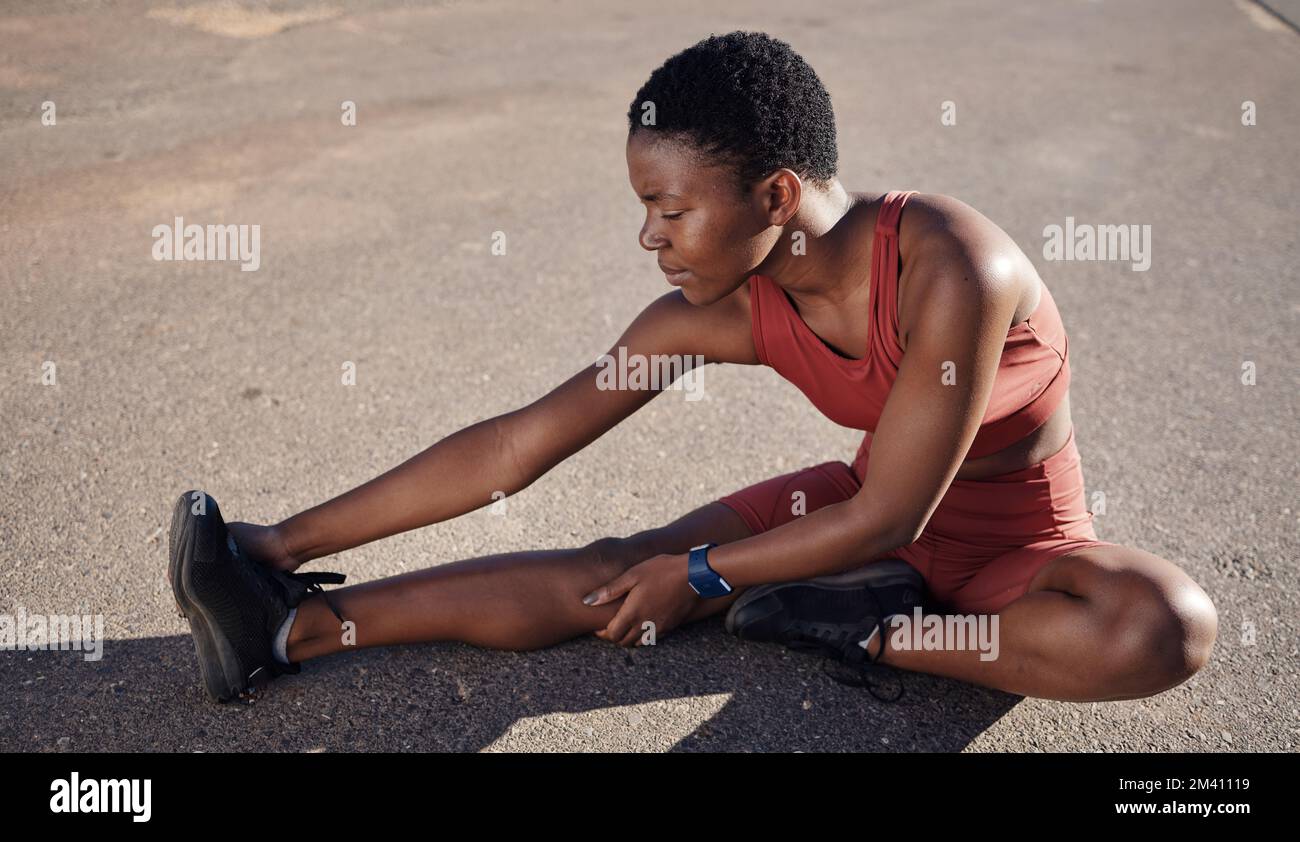 Donna nera, fitness o gambe stretching sulla strada della città per alleviare il dolore muscolare, il benessere sanitario o la tensione del corpo. Runner, atleta o persona sportiva Foto Stock