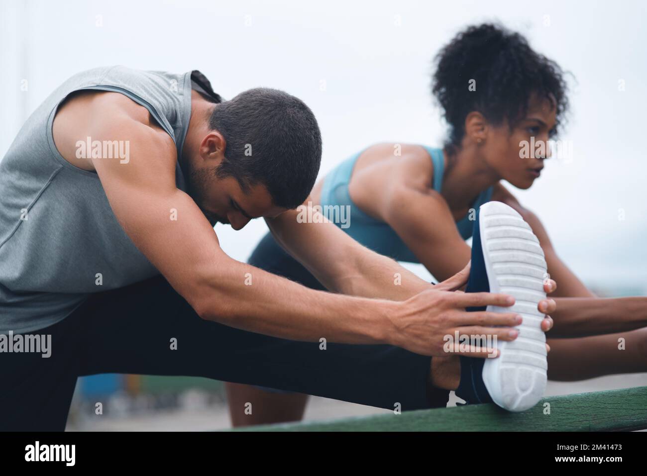 Lo stretching è importante e dovrebbe essere parte della nostra routine di corsa. due giovani sportivi che si allungano mentre si allenano all'aperto. Foto Stock