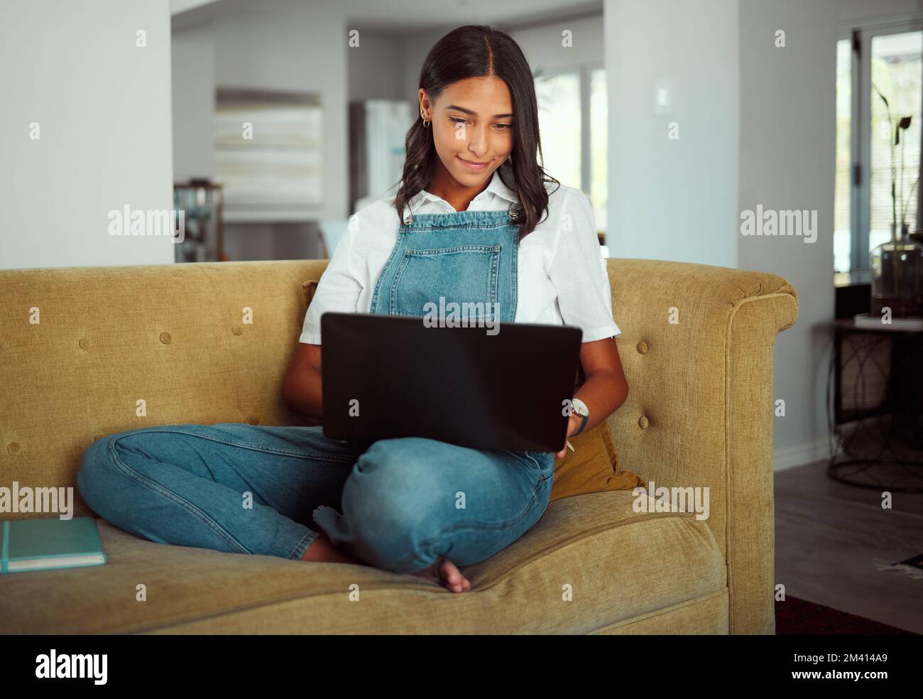 Donna, computer portatile o rilassarsi sul divano in casa o nel salotto di casa per e learning, istruzione o studio di blocco. Sorridere, felice o studente sulla tecnologia per Foto Stock