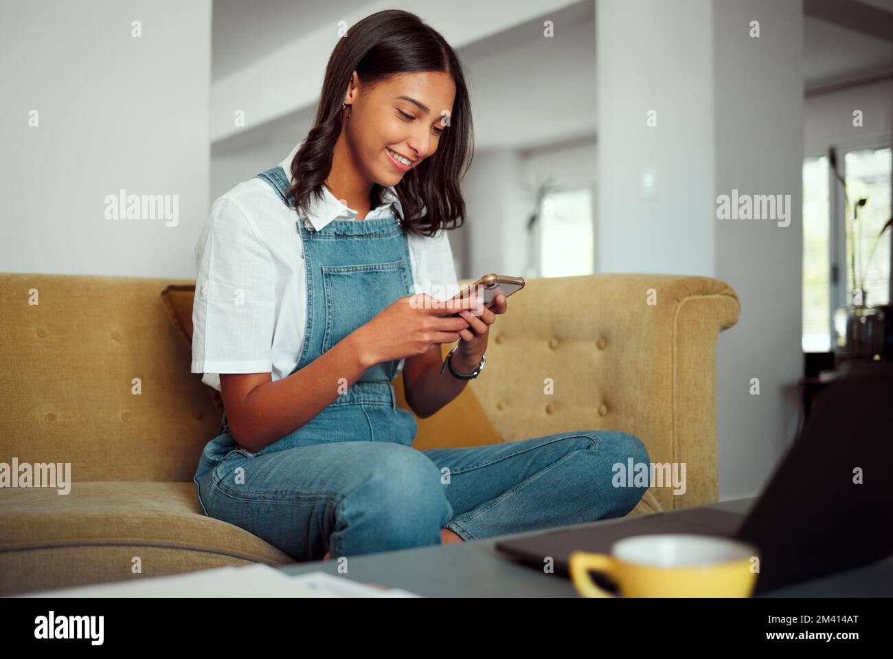 Donna, telefono e social media lettura mobile di una persona rilassarsi sul divano di casa. Invio di SMS su Internet, web e social network di una giovane donna Foto Stock