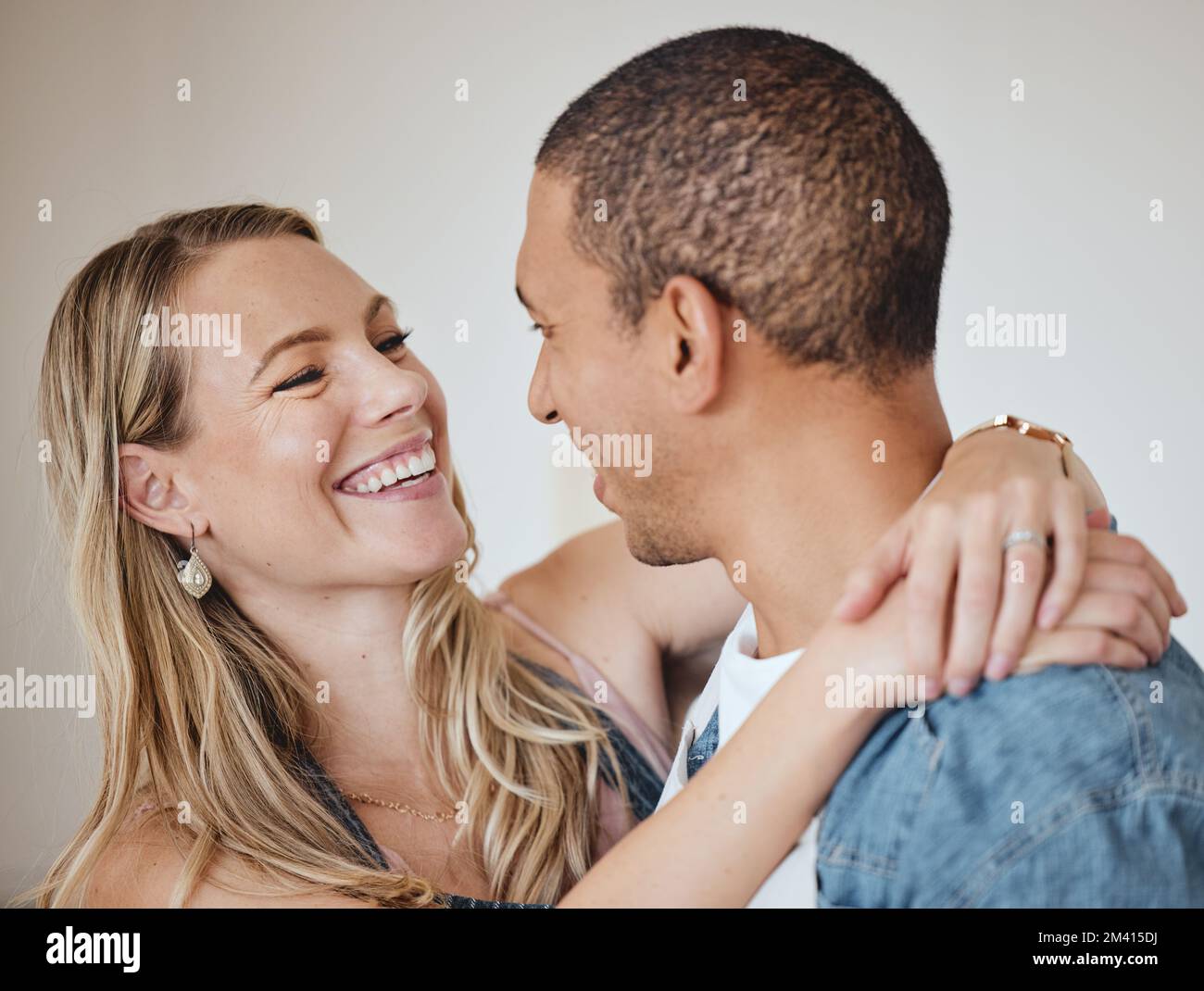 Amate, abbracciatevi e sorridete con una coppia diversificata in studio su uno sfondo grigio per romanticismo o affetto. Fiducia, sicurezza e con un uomo e una donna Foto Stock