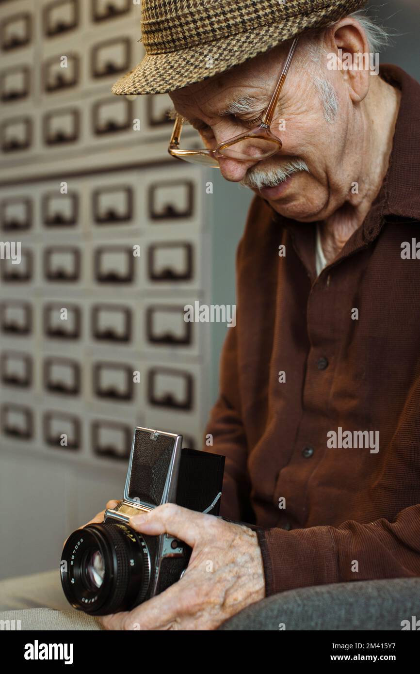 Un vecchio fotografo con una videocamera di medio formato nelle sue mani. Foto Stock