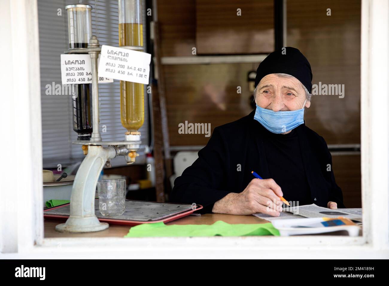 Interessanti scene dal mercato locale quotidiano nella città di Ozurgeti vicino alla costa di un Mar Rosso, donna, un venditore che legge un libro mentre vende, Georgia Foto Stock
