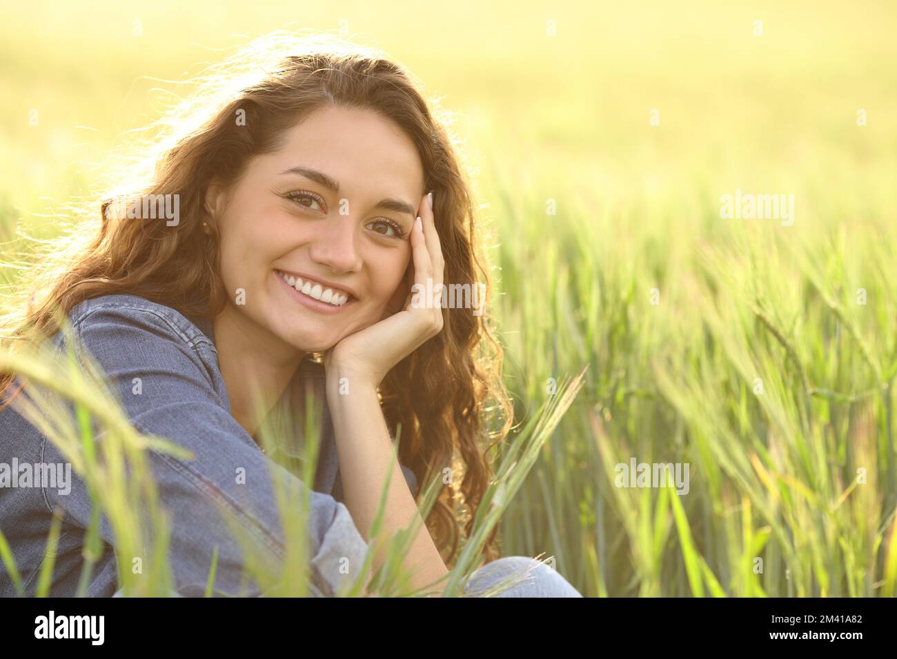 Bella donna felice sorridente alla macchina fotografica in un campo di grano Foto Stock