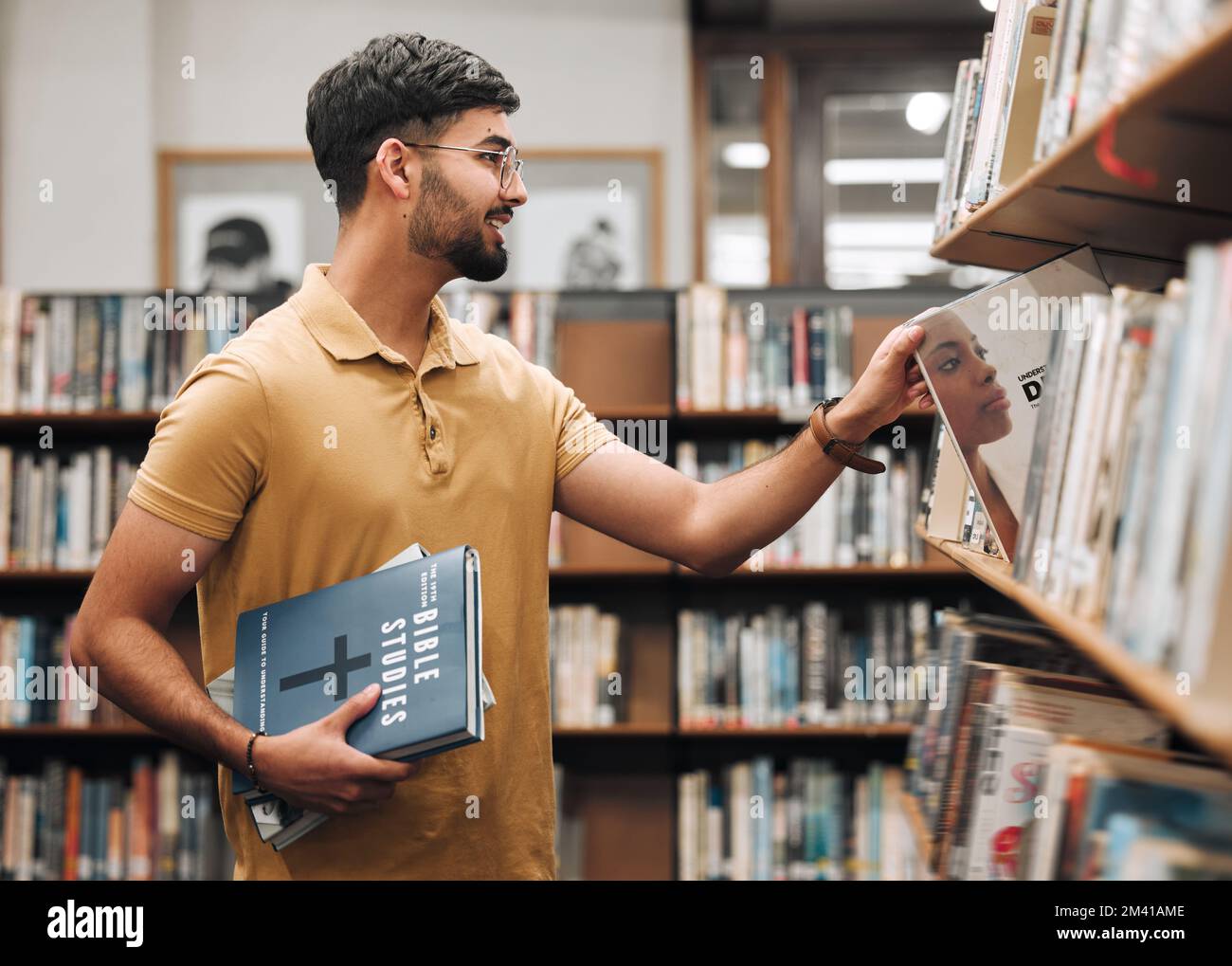 Università, studente o uomo con la bibbia in una biblioteca per studiare la conoscenza della religione spirituale, la preghiera o la ricerca di Cristo libreria. Sorridete, scolastiche o felici Foto Stock
