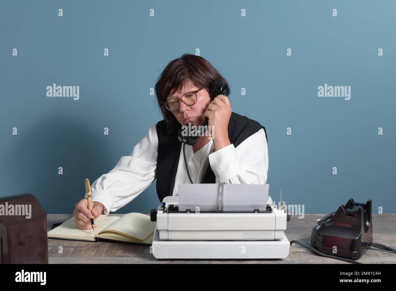 Una segretaria del passato al lavoro. Tavolo con telefono e macchina da scrivere. Vintage Foto Stock