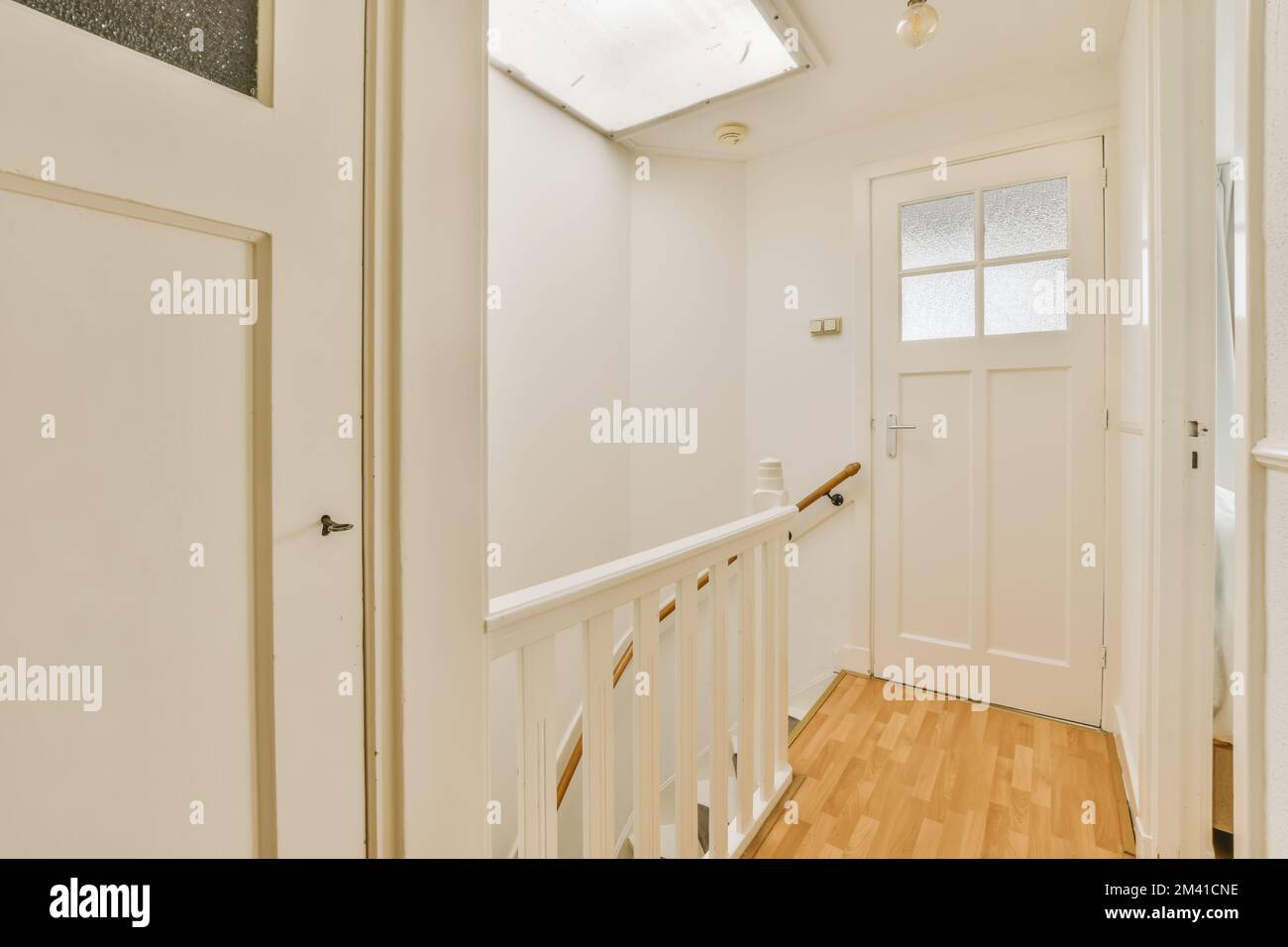 una stanza vuota con pareti bianche e pavimento in legno la porta è aperta sul lato destro della stanza Foto Stock