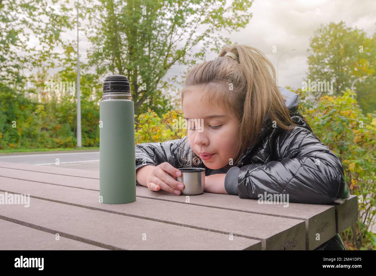 Bevanda calda in una passeggiata autunnale nella natura. Ragazza che beve da un thermos Foto Stock