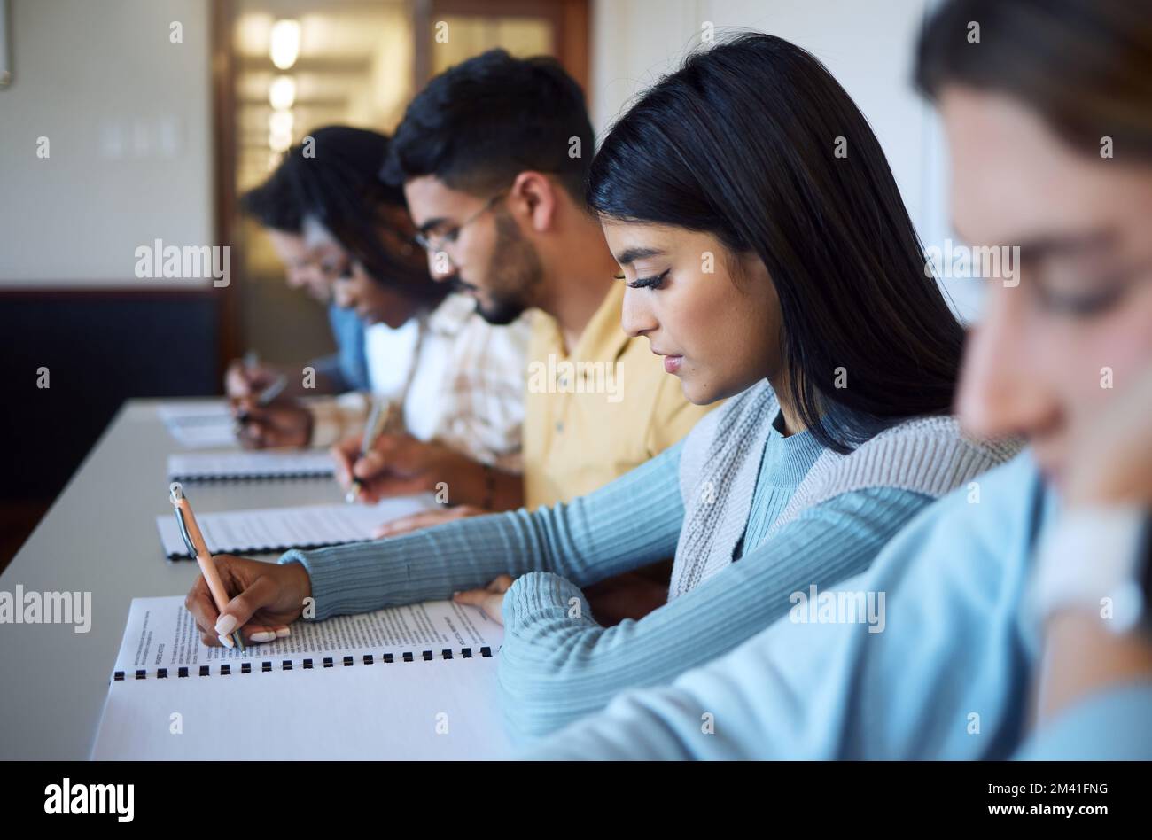 Studenti, scrivendo un esame e studiando in aula per l'istruzione, l'apprendimento universitario e il documento di prova. Giovani universitari, conoscenze e borse di studio Foto Stock