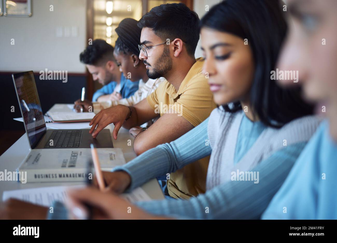 Studenti, libri sulla diversità e su computer portatile in aula, lezioni e studi in biblioteca per l'istruzione, la ricerca e l'apprendimento. Gruppo scolastico, gente del college e. Foto Stock