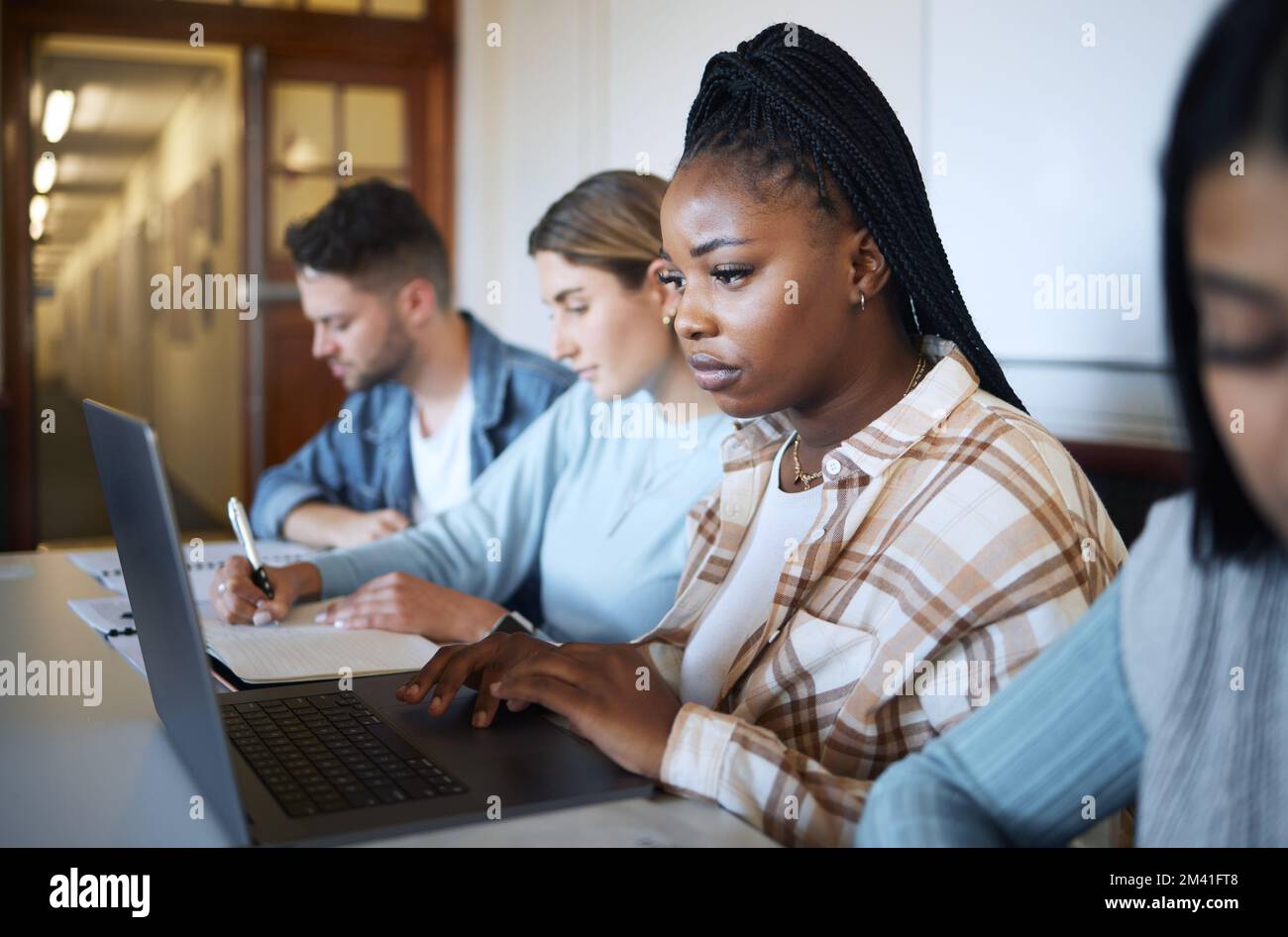 Università, formazione e gruppo di studenti alla scrivania che si dedicano al progetto, allo studio e all'apprendimento con notebook e notebook. Accademia, college e giovani Foto Stock