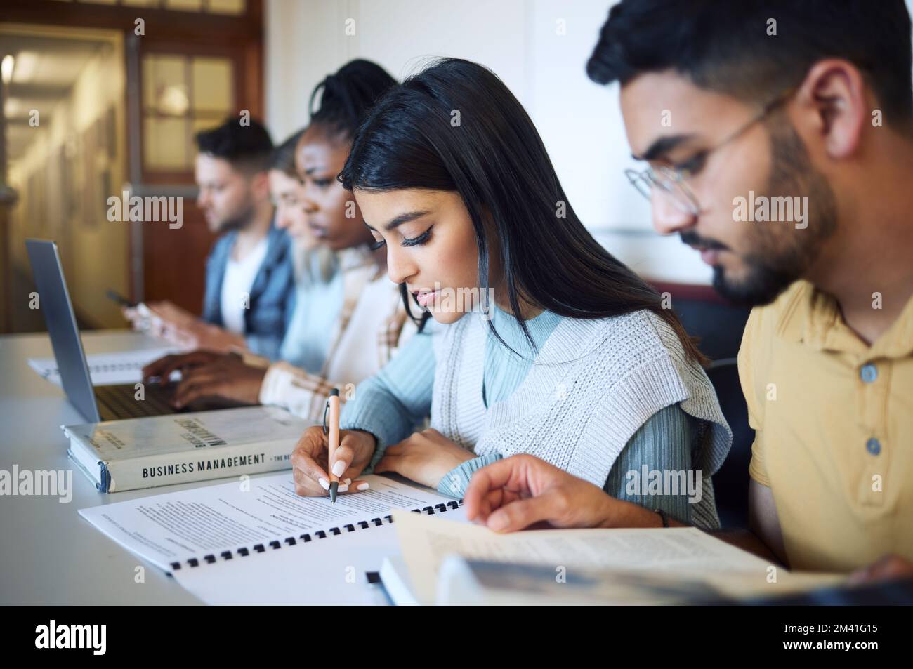 Università, formazione e studenti che studiano per esami, test o compiti nella biblioteca del campus. Borse di studio, conoscenze e giovani amici che imparano Foto Stock