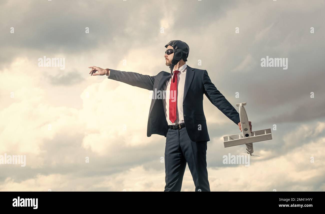 uomo d'affari in tuta e cappello pilota lancio aereo giocattolo su sfondo cielo. startup Foto Stock