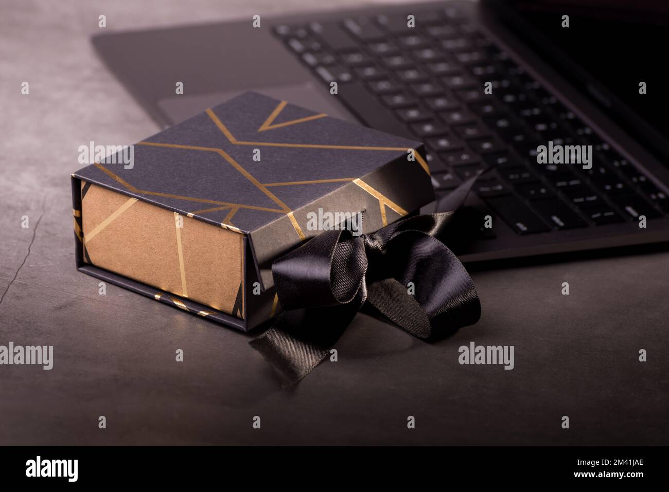 Confezione regalo nera decorata con strisce dorate su una tastiera per computer portatile. Regali per gli uomini. Buon per i Banners in linea di acquisto del giorno del padre o del venerdì nero. Foto Stock