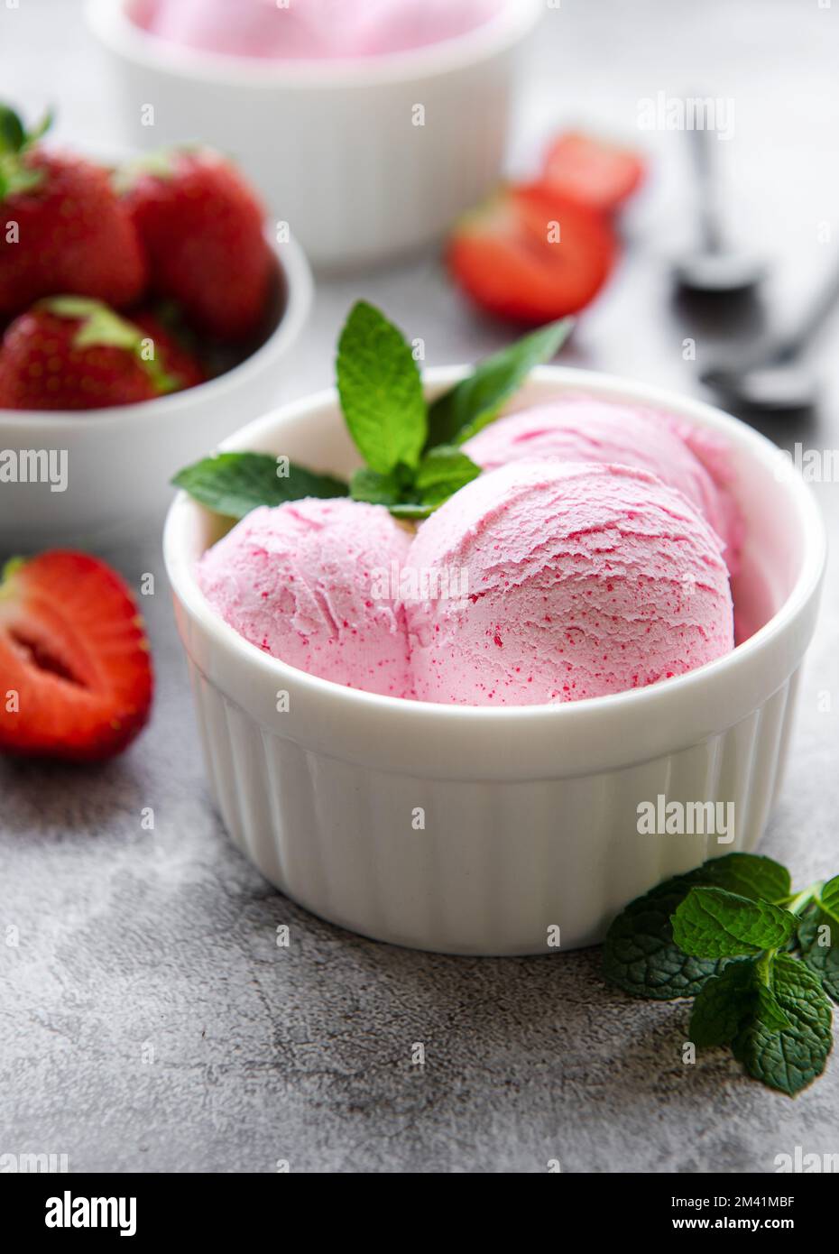 Gelato alla fragola fatto in casa con fragole fresche. Dolce bacche dessert estate. Sfondo concreto Foto Stock