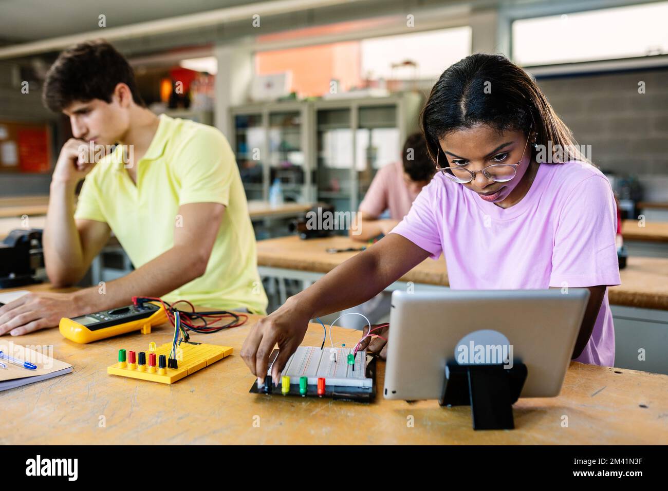 Giovane studentessa latina ispanica che impara l'elettronica alla lezione di scuola superiore Foto Stock