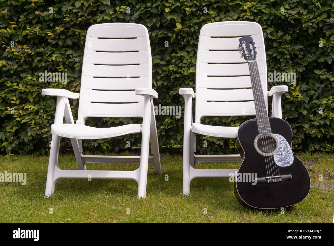 Fine estate. Sedie da spiaggia vuote e una chitarra dimenticata Foto Stock