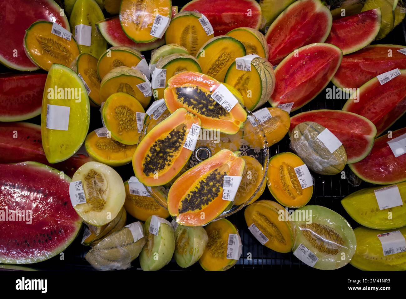 Melone cantaloupe, anguria e papaya, tagliato a metà confezionato in pellicola di plastica esposta e prezzo in euro per la vendita in frigo supermercato, vista dall'alto, rea Foto Stock