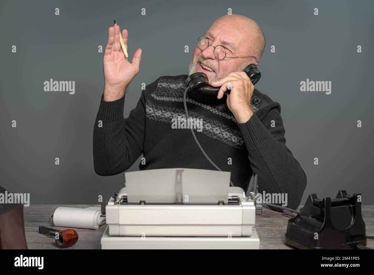 Ritratto vintage. L'autore giornalista ride. Tavolo con telefono e macchina da scrivere. Redattore del produttore Foto Stock