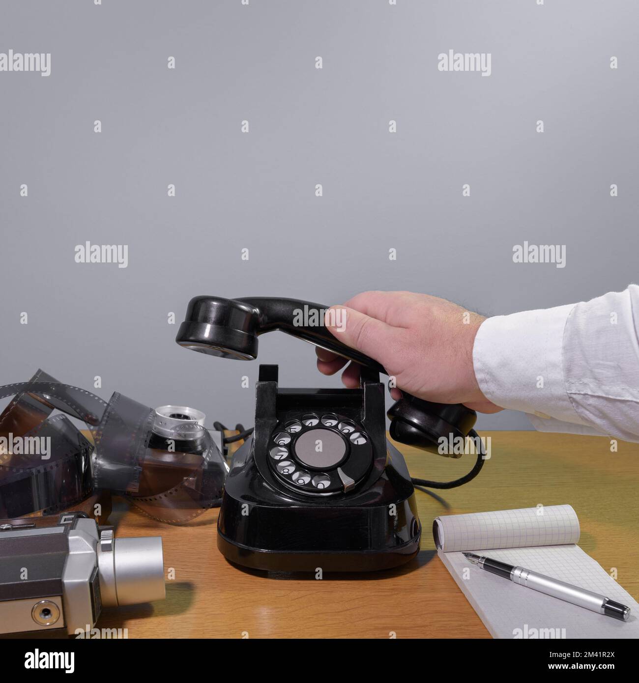 La mano di un giornalista raggiunge per il telefono. Vecchio apparecchio telefonico su un tavolo di legno, installazione retrò. Spazio di copia Foto Stock