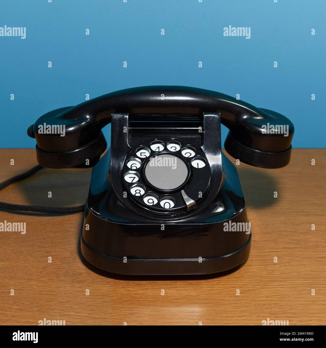 vecchio telefono su un tavolo di legno, sfondo blu. formato quadrato Foto Stock