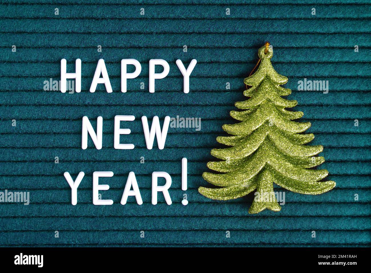 Felice anno nuovo , testo su cartoncino in feltro turchese scuro con lettere bianche e abete giocattolo verde decorativo . Vista dall'alto, disposizione piatta Foto Stock